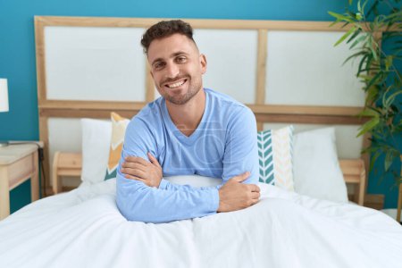 Photo for Young hispanic man smiling confident sitting on bed at bedroom - Royalty Free Image