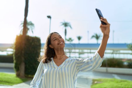 Téléchargez les photos : Jeune femme afro-américaine souriante confiante faire selfie par le smartphone à la terrasse du café - en image libre de droit