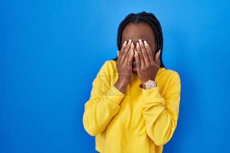 Photo for Beautiful black woman standing over blue background rubbing eyes for fatigue and headache, sleepy and tired expression. vision problem - Royalty Free Image