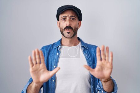 Photo for Hispanic man with beard standing over isolated background moving away hands palms showing refusal and denial with afraid and disgusting expression. stop and forbidden. - Royalty Free Image