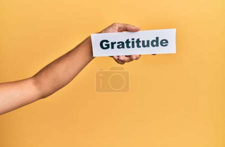 Hand of caucasian man holding paper with gratitude word over isolated white background