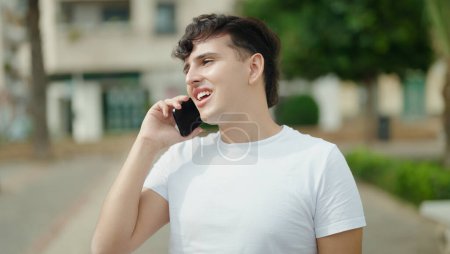 Photo for Non binary man smiling confident talking on smartphone at park - Royalty Free Image