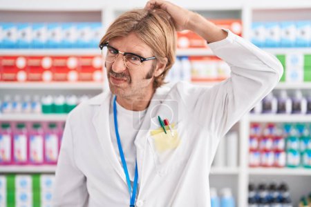 Téléchargez les photos : Homme caucasien avec moustache travaillant à la pharmacie pharmacie confondre et s'interroger sur la question. incertain avec doute, pensant la main sur la tête. concept coûteux. - en image libre de droit