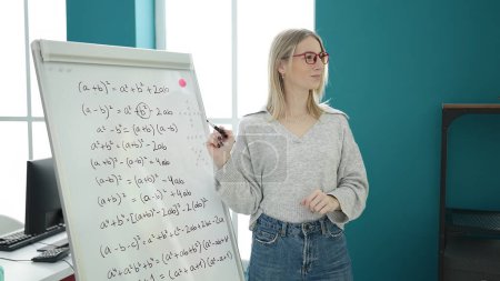 Foto de Joven mujer rubia enseñando matemáticas en el tablero magnético en la universidad de la biblioteca - Imagen libre de derechos