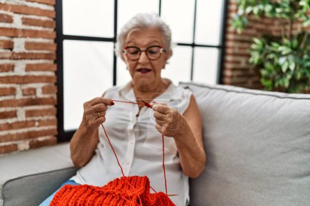 Photo for Senior grey-haired woman sewing using lane and needle at home - Royalty Free Image