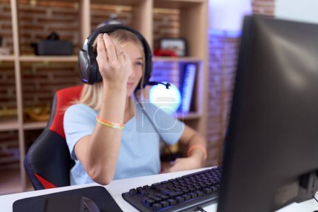 Photo for Young caucasian woman playing video games wearing headphones doing italian gesture with hand and fingers confident expression - Royalty Free Image
