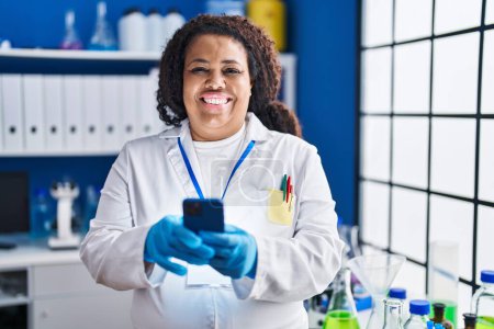 Photo for African american woman scientist smiling confident using smartphone at laboratory - Royalty Free Image