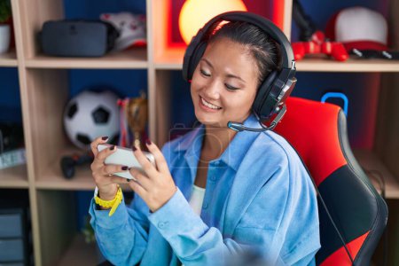 Foto de Joven mujer china streamer jugando videojuegos con teléfono inteligente en la sala de juegos - Imagen libre de derechos