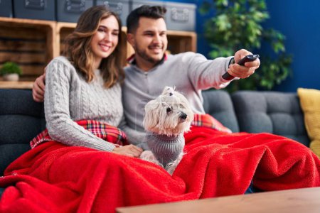 Téléchargez les photos : Man and woman watching movie sitting on sofa with dog at home - en image libre de droit