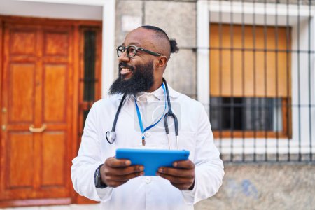 Téléchargez les photos : Jeune homme afro-américain portant l'uniforme de médecin en utilisant le pavé tactile à l'hôpital - en image libre de droit