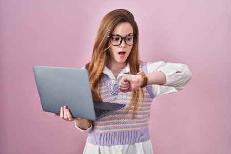 Foto de Mujer caucásica joven que trabaja con computadora portátil mirando el tiempo reloj preocupado, miedo de llegar tarde - Imagen libre de derechos