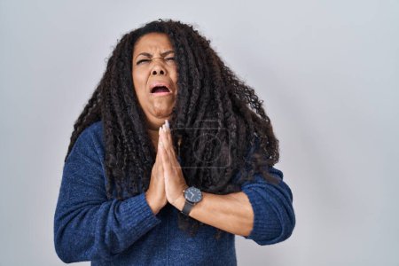Photo for Plus size hispanic woman standing over white background begging and praying with hands together with hope expression on face very emotional and worried. begging. - Royalty Free Image