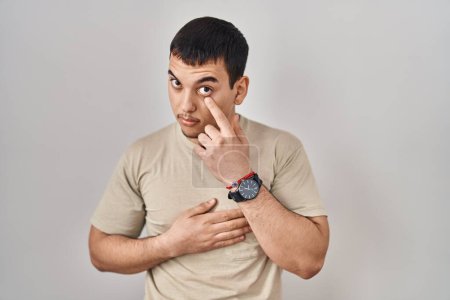 Téléchargez les photos : Jeune homme arabe portant t-shirt décontracté pointant vers l'oeil vous regarder geste, expression suspecte - en image libre de droit