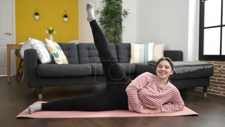 Photo for Young blonde woman smiling confident training legs exercise at home - Royalty Free Image