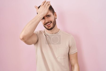 Téléchargez les photos : Homme hispanique avec barbe debout sur fond rose surpris avec la main sur la tête pour erreur, rappelez-vous erreur. oublié, mauvais concept de mémoire. - en image libre de droit