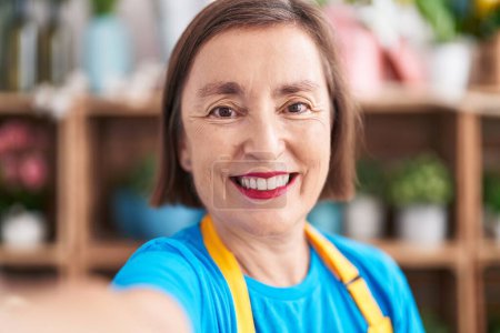 Photo for Middle age woman florist smiling confident make selfie by camera at flower shop - Royalty Free Image