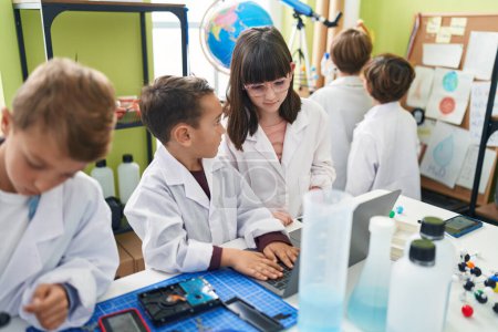 Téléchargez les photos : Groupe d'enfants scientifiques étudiants utilisant un ordinateur portable dans une salle de classe de laboratoire - en image libre de droit