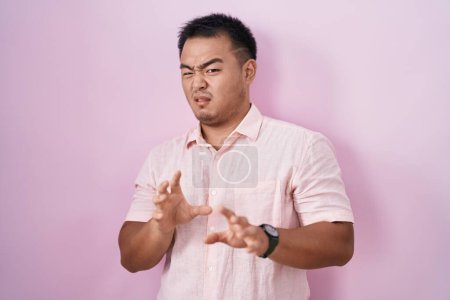 Téléchargez les photos : Jeune homme chinois debout sur fond rose expression dégoûtée, mécontent et effrayé faire visage dégoût parce que réaction d'aversion. - en image libre de droit