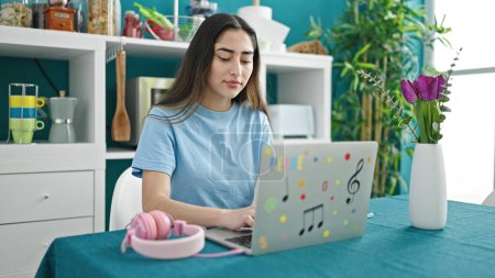 Photo for Young beautiful hispanic woman using laptop studying at dinning room - Royalty Free Image