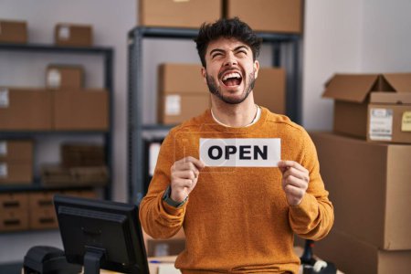 Photo for Hispanic man with beard working at small business ecommerce holding open sign angry and mad screaming frustrated and furious, shouting with anger looking up. - Royalty Free Image