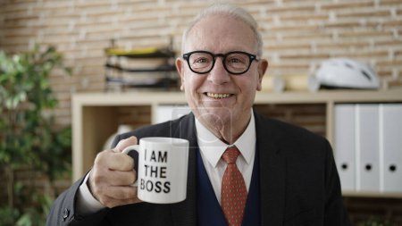 Foto de Senior sonriendo confiado sosteniendo soy el jefe taza de café en la oficina - Imagen libre de derechos