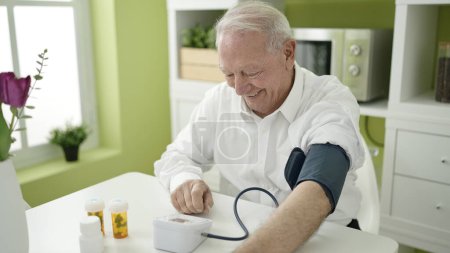 Photo for Senior measuring pulse using tensiometer at home - Royalty Free Image