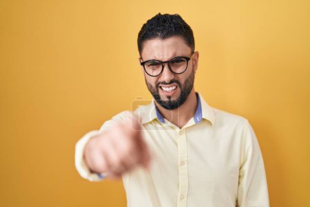 Téléchargez les photos : Jeune homme hispanique portant des vêtements de travail et des lunettes pointant mécontent et frustré à la caméra, en colère et furieux contre vous - en image libre de droit