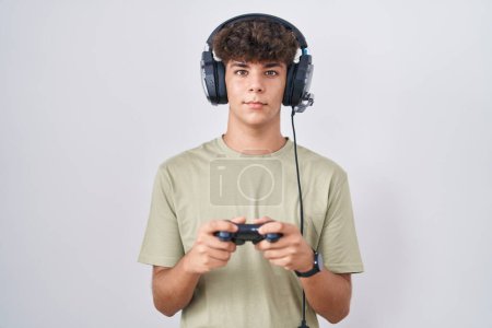 Foto de Adolescente hispano jugando a videojuegos sosteniendo el controlador con una sonrisa alegre y fresca en la cara. persona afortunada. - Imagen libre de derechos