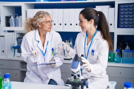 Téléchargez les photos : Deux femmes scientifiques au microscope écrivent sur un document au laboratoire - en image libre de droit