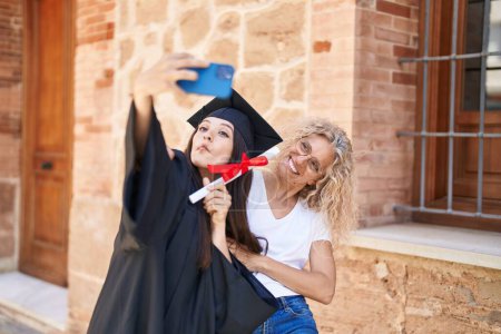 Photo for Two women mother and graduated daughter make selfie by smartphone at campus university - Royalty Free Image