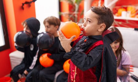 Téléchargez les photos : Groupe d'enfants portant un costume d'Halloween gonflant des ballons à la maison - en image libre de droit