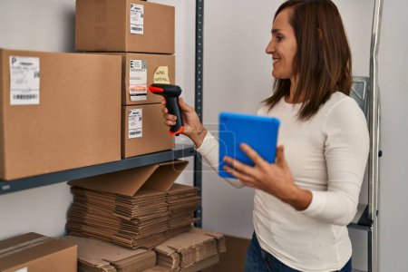 Téléchargez les photos : Middle age woman ecommerce business worker scanning package using barcode reader at office - en image libre de droit