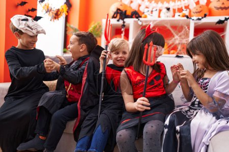 Foto de Grupo de niños con disfraz de Halloween haciendo gesto de miedo en casa - Imagen libre de derechos