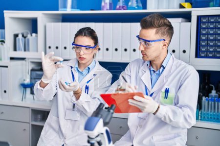 Téléchargez les photos : Homme et femme scientifiques tenant des pilules écrivent sur le document au laboratoire - en image libre de droit