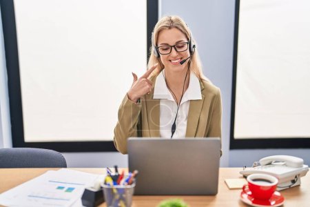 Photo for Young caucasian woman working wearing call center agent headset smiling happy pointing with hand and finger - Royalty Free Image