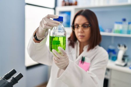 Foto de Joven hermosa mujer hispana científica midiendo líquido en laboratorio - Imagen libre de derechos