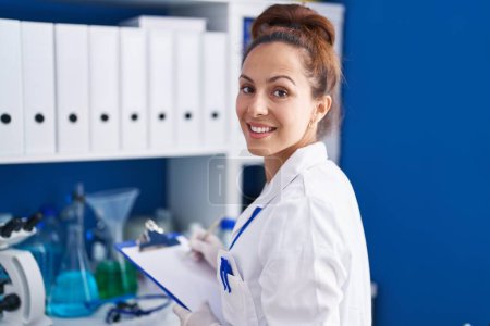 Photo for Young woman scientist writing on document working at laboratory - Royalty Free Image