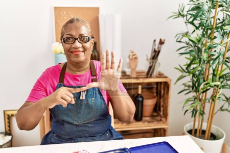 Foto de Mujer afroamericana mayor comunicándose con lenguaje sordo en estudio de arte - Imagen libre de derechos