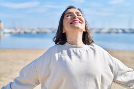Téléchargez les photos : Middle age woman smiling confident breathing at seaside - en image libre de droit