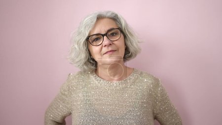 Téléchargez les photos : Middle age woman with grey hair standing with serious expression over isolated pink background - en image libre de droit