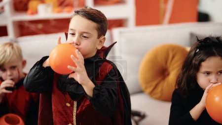 Foto de Grupo de niños con disfraz de halloween inflando globos en casa - Imagen libre de derechos