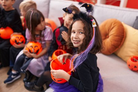 Photo for Group of kids wearing halloween costume holding pumpkin basket at home - Royalty Free Image