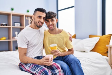 Foto de Dos hombre pareja bebiendo café sentado en la cama en el dormitorio - Imagen libre de derechos