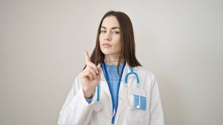 Junge kaukasische Ärztin sagt Nein mit dem Finger über isolierten weißen Hintergrund