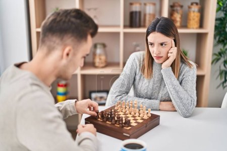 Téléchargez les photos : Homme et femme couple jouer aux échecs assis sur la table à la maison - en image libre de droit