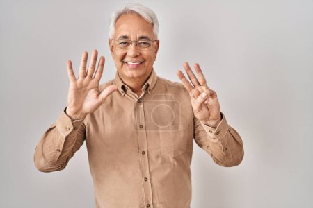 Téléchargez les photos : Hispanic senior man wearing glasses showing and pointing up with fingers number eight while smiling confident and happy. - en image libre de droit