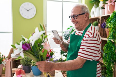Photo for Middle age grey-haired man florist make photo to flowers by smartphone at flower shop - Royalty Free Image