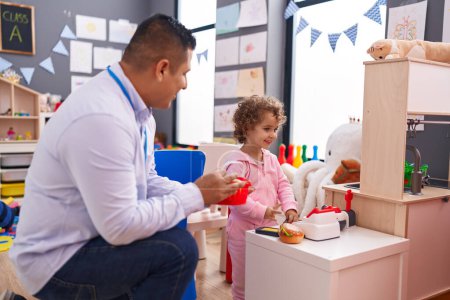 Photo for Hispanic man and girl playing supermarket game sitting on table at kindergarten - Royalty Free Image