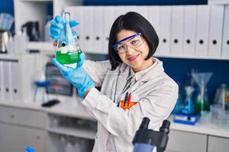 Photo for Young chinese woman scientist measuring liquid at laboratory - Royalty Free Image