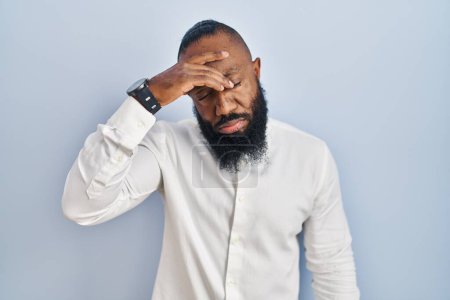 Téléchargez les photos : Homme afro-américain debout sur fond bleu inquiet et stressé par un problème avec la main sur le front, nerveux et anxieux pour la crise - en image libre de droit